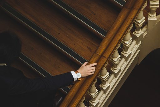 A hand resting on a grand wooden staircase banister